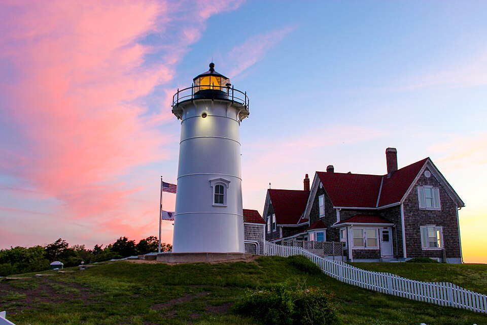 Iconic Cape Cod lighthouse overlooking pristine sandy beaches and Atlantic Ocean at golden hour